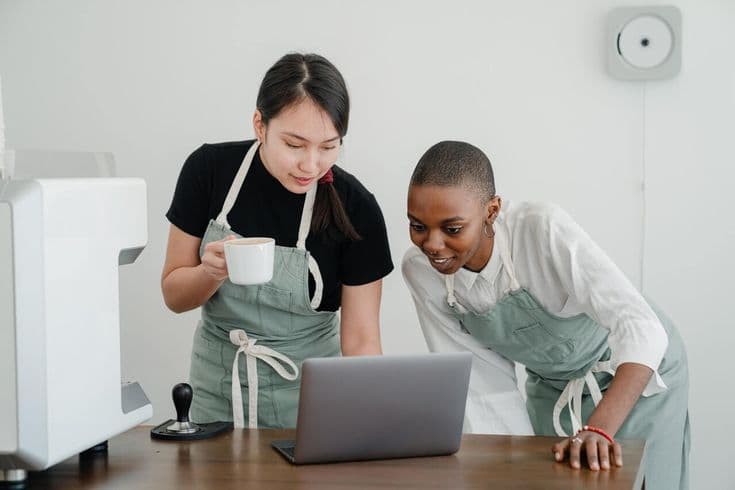 Two hospitality staff reviewing figures together on a laptop
