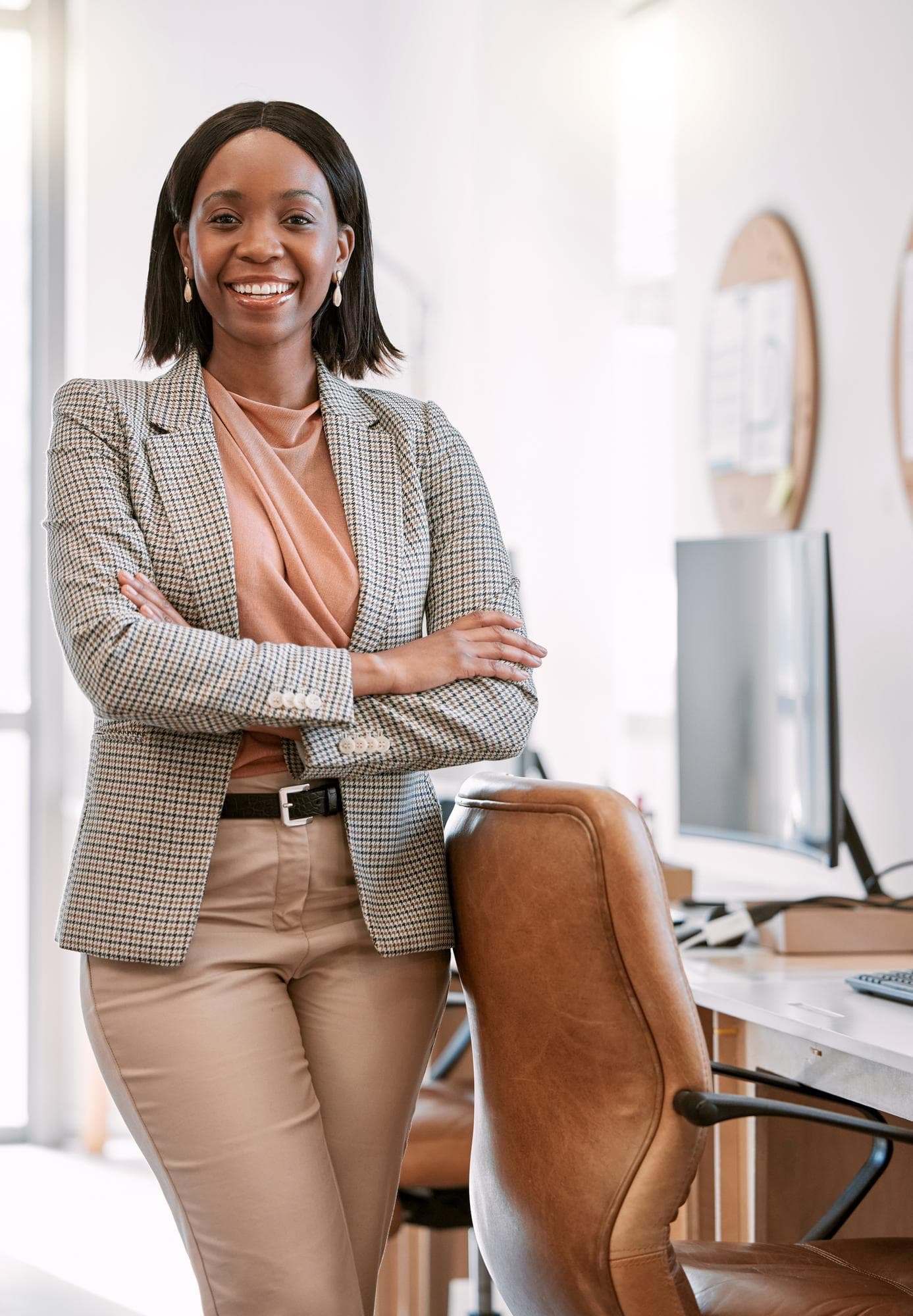 A smiling professional standing with arms crossed in an office